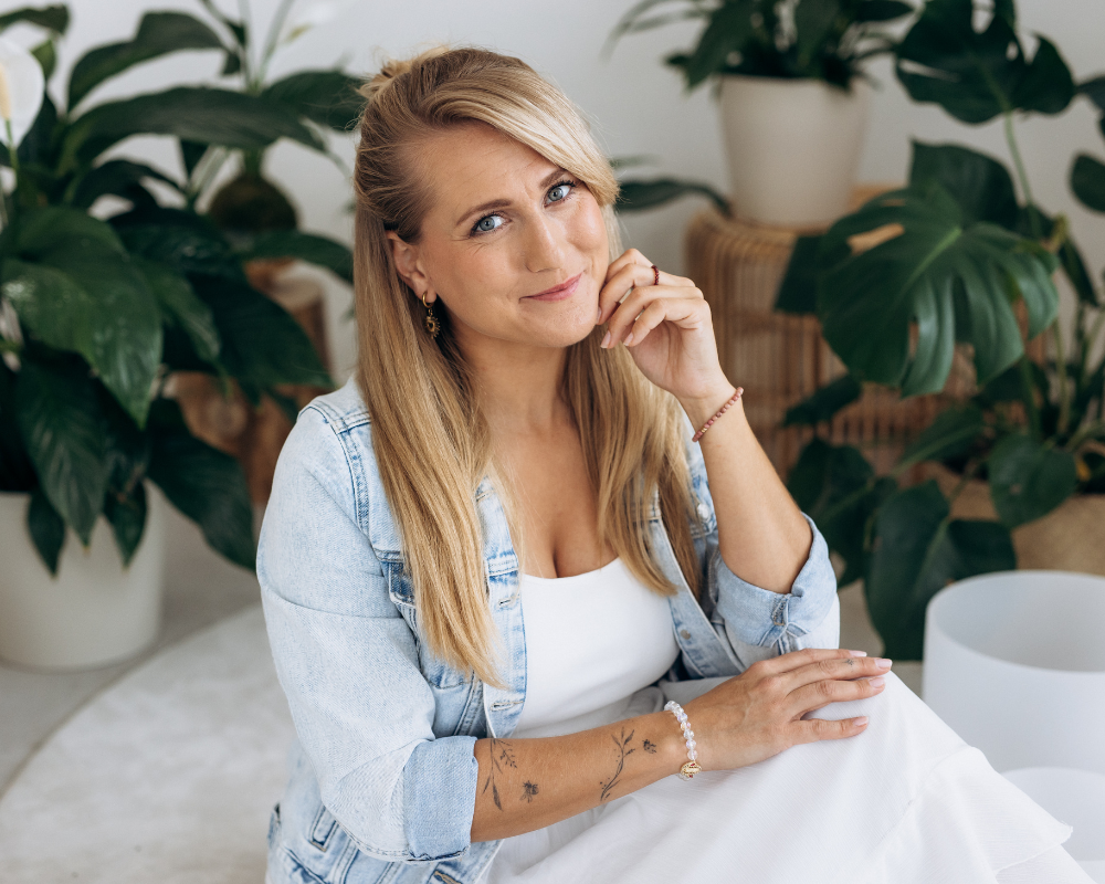 Kristy Stehnová z projektu RestartujSe s Kristy sedí v klidném prostoru, jemný portrét s přirozeným výrazem. Je obklopena květinami a křišťálovými mísami.